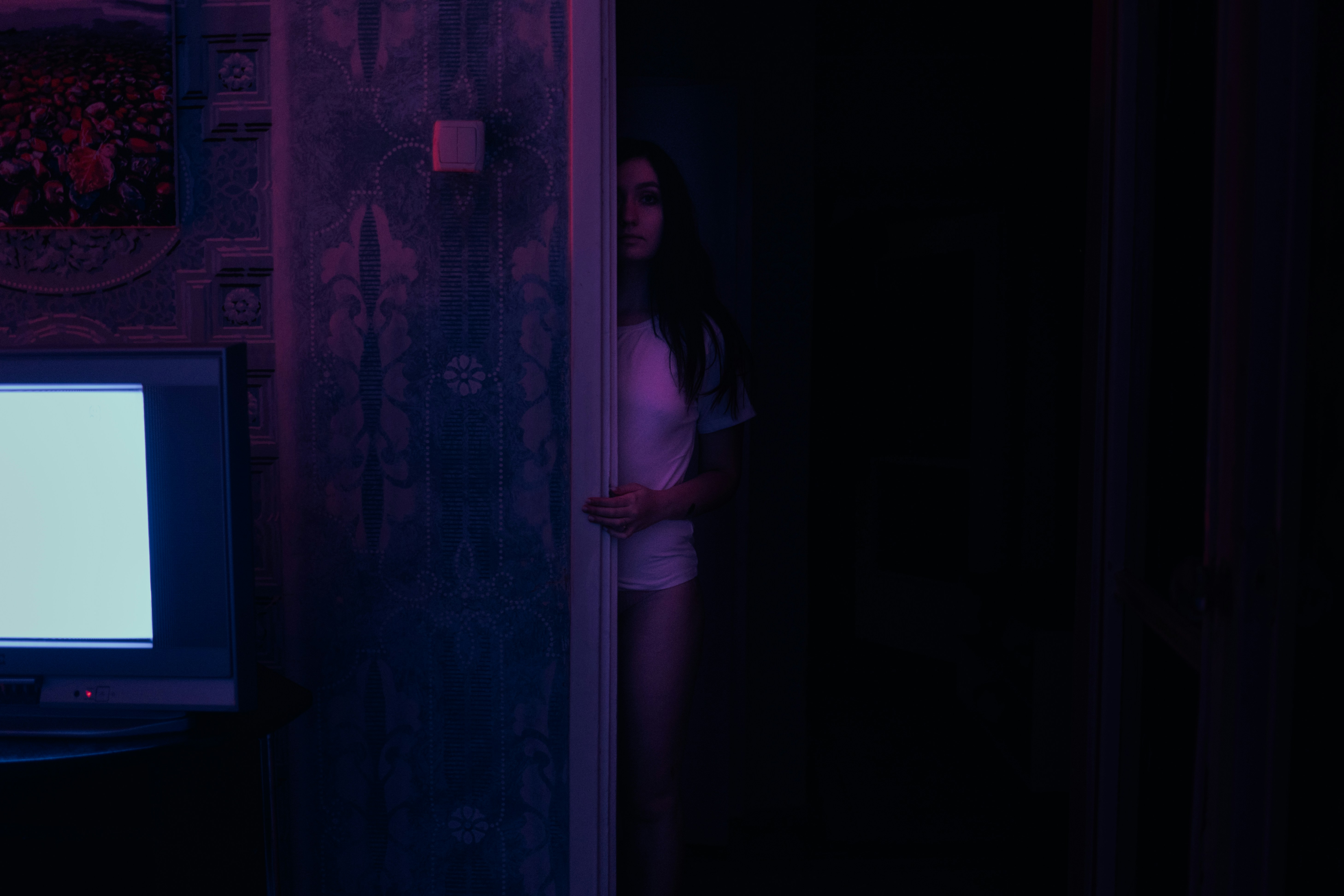 Woman watching content in a darkened room with TV illumination